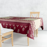Red patterned Christmas tablecloth draped over table with festive diamond and snowflake motifs