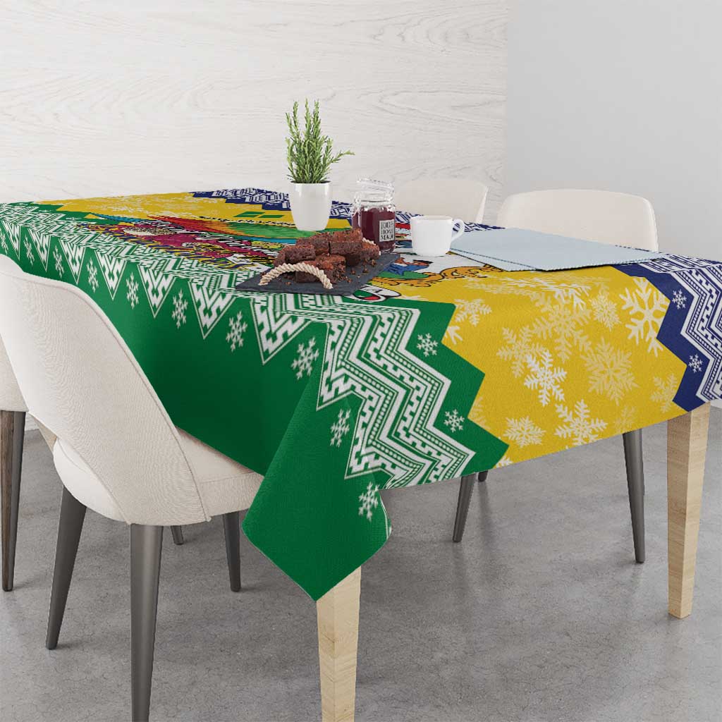 Green and yellow Christmas tablecloth with blue border and patterned trim, draped on table