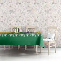 Green Christmas tablecloth with patterned border across dining table and matching chairs