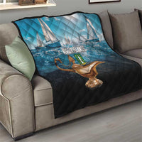 Blue and black quilt laid on sofa showing sailboats, Virgin Islands text, and gold lamp