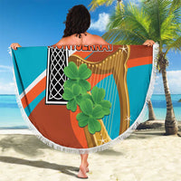 Round beach blanket with white fringe, orange teal cross design held outdoors on sand