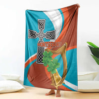 Teal, white, and rust blanket with large cross-harp symbol and clover