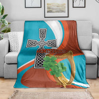 Teal, white, and rust blanket with cross-harp emblem and centered clover