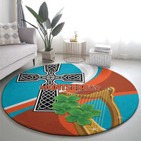 Round rug with circular teal, rust, and gray abstract pattern featuring black cross, harp, green plant