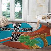 Round rug with teal and rust orange abstract harp-and-cross artwork, green shamrock-like leaves