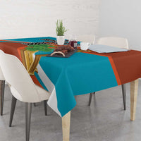 Teal and rust tablecloth with gold harp and black cross motif, draped on table