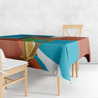 Teal and rust tablecloth with gold harp and black cross motif, hanging over table edge
