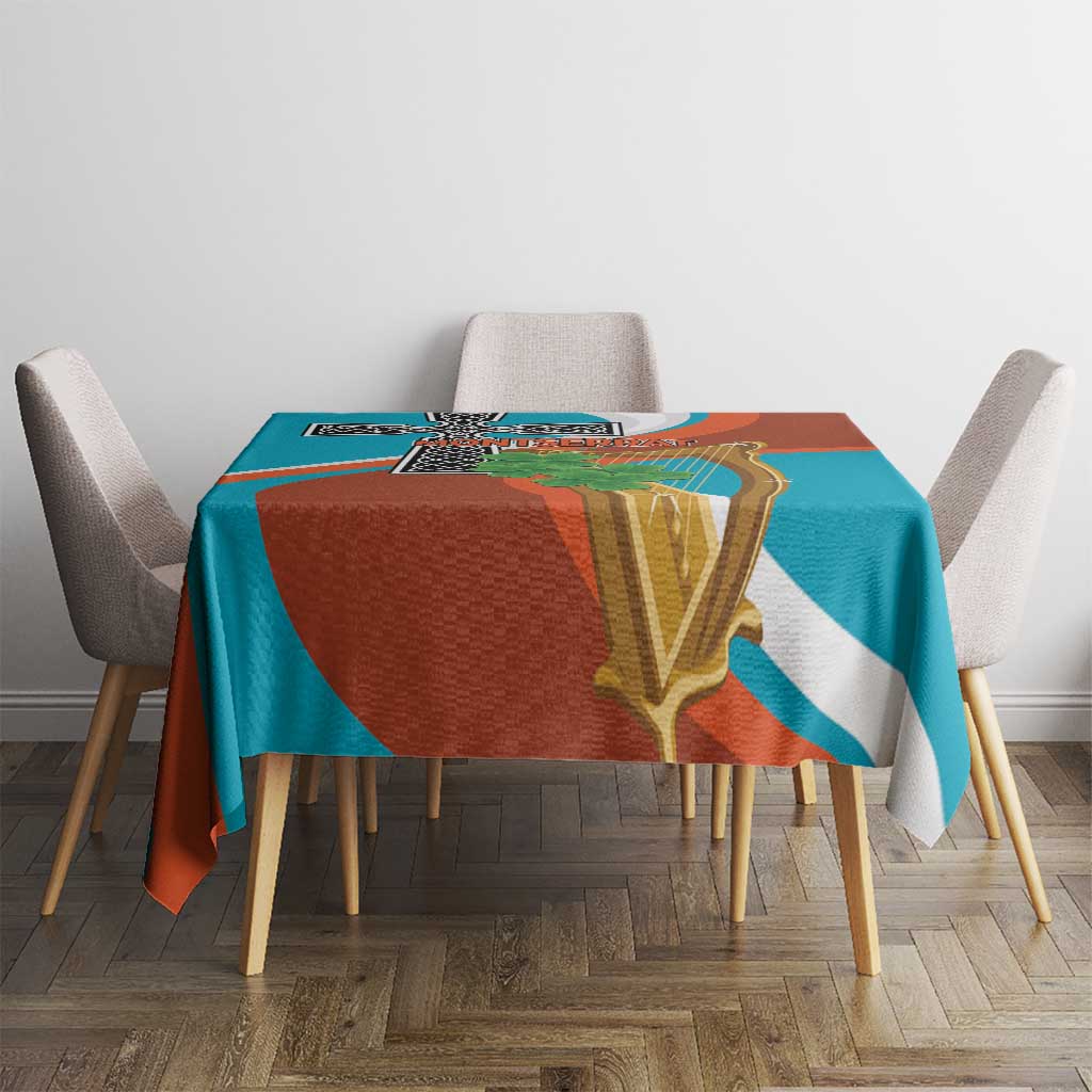 Teal and rust tablecloth with gold harp and black cross motif, set across table