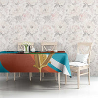 Teal and rust tablecloth with gold harp and black cross motif, on long dining table