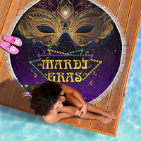 Purple round beach blanket with gold carnival mask and Mardi Gras lettering, white fringe edge