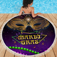 Purple round beach blanket with gold mask design and Mardi Gras lettering, tassel fringe edge