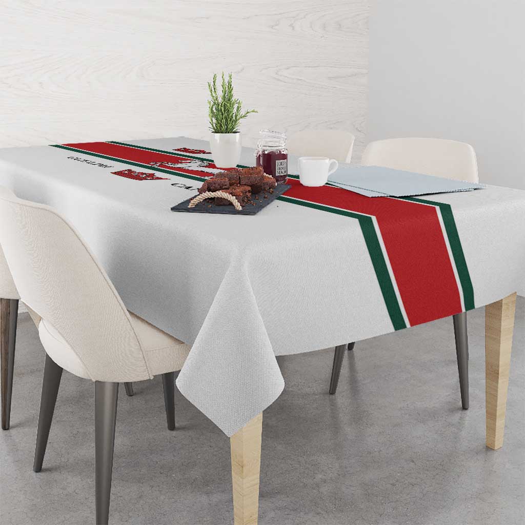 White tablecloth with red-and-green trim and crown and horse print across center