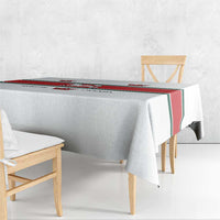 White tablecloth draped over table with red-green border and crest pattern