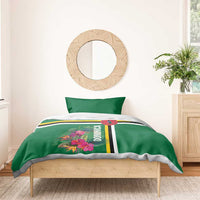 Green bedding set on bed with tropical flower print, Dominica lettering, and striped trim