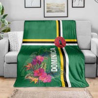 Green tropical blanket with Dominica text, pink flowers, and striped bands on sofa