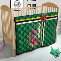 Green quilt for baby with tropical floral print, striped bands, oval emblem, and Dominica text