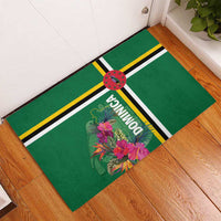 Green rubber doormat with tropical flowers, “Dominica” text, and yellow/black striped border