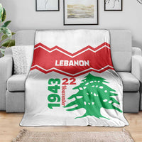 White Lebanon independence day blanket draped on a sofa, red chevrons and green cedar