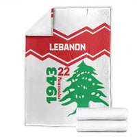 Folded white Lebanon independence day blanket with red zigzags and green cedar tree