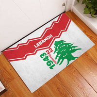 Rubber doormat in room corner, red zigzag border with Lebanon and green cedar crest