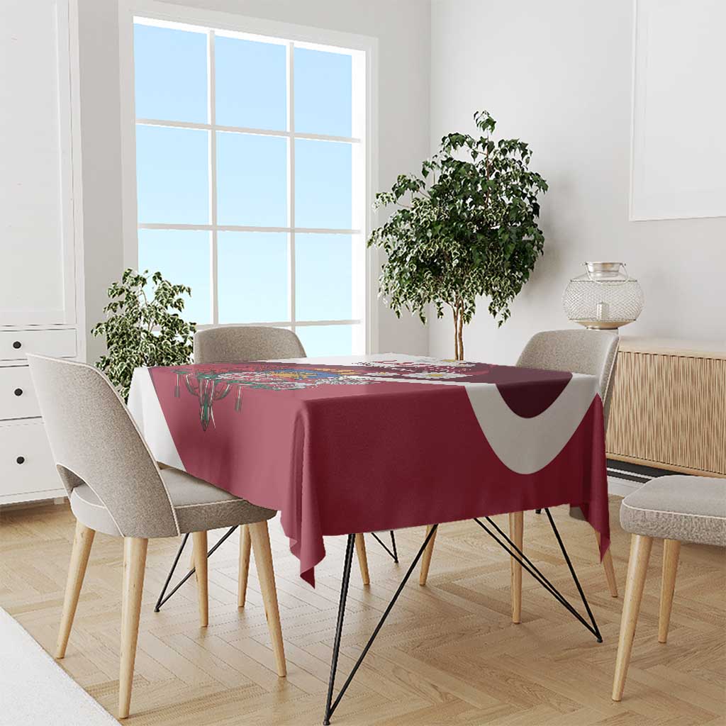 Red tablecloth draped over dining table with Latvia crest and daisy border
