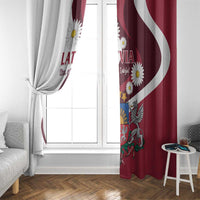 Red and white Latvian flag curtain panels, tied at the side, with daisies and crest.
