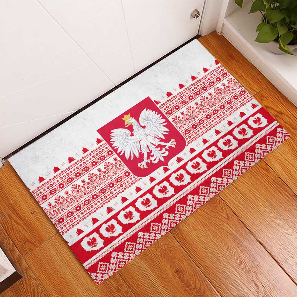 White rubber doormat laid at entry with red Polish crest and decorative folk bands