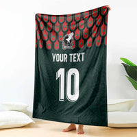 Dark green blanket with Mexican crest, number 10, and red-teal scalloped pattern