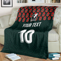 Dark green blanket on couch with Mexican crest, number 10, and red-teal pattern