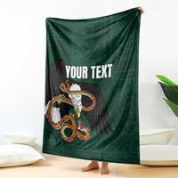 Green throw blanket draped with eagle-and-serpent graphic and 'YOUR TEXT' text.