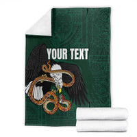 Green throw blanket with eagle-and-serpent graphic and 'YOUR TEXT', plus folded white towels.