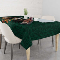 Green tablecloth draped over dining table, featuring bold eagle emblem and pattern.