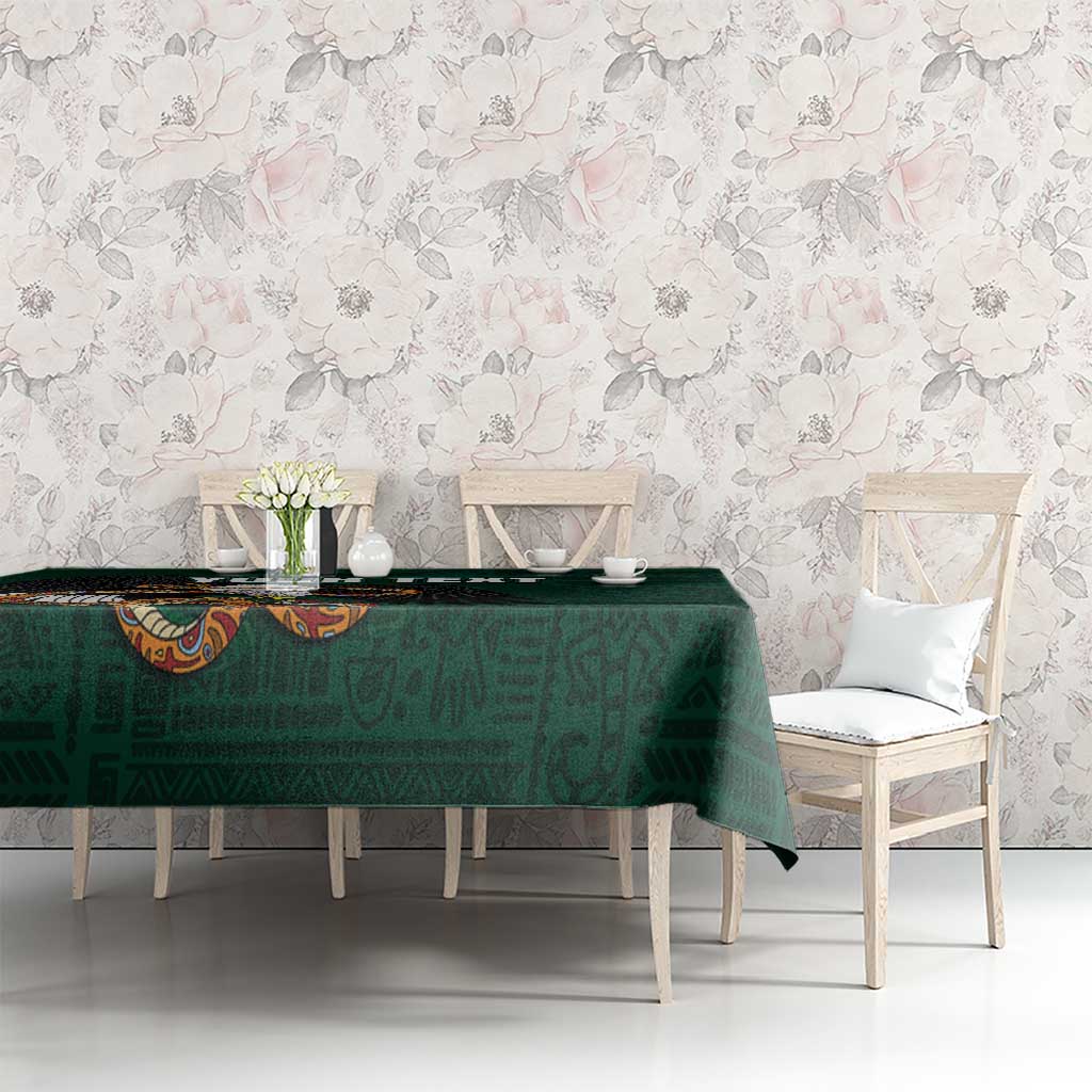 Green tablecloth on dining table with subtle tribal print and eagle emblem detail.