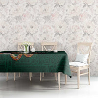 Green tablecloth on dining table with subtle tribal print and eagle emblem detail.