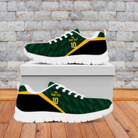 Green lace-up sneakers with white sole and yellow stripe, on display