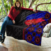 African flag-style quilt draped on couch, black with blue and red diagonal stripe and rings