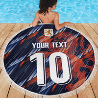 Navy circular fringe beach blanket with crest, “YOUR TEXT,” and large “10” on wooden deck