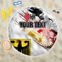 Round white beach blanket with eagle graphic, red and black streaks, and fringed edge