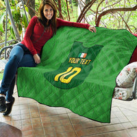 Green quilt laid over a person’s lap, featuring crest, “YOUR TEXT”, and yellow “10”.
