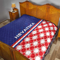 Blue and red check quilt laid on bed, HRVATSKA stripe along the seam