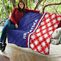 Blue and red check quilt draped on a couch, HRVATSKA stripe on the edge