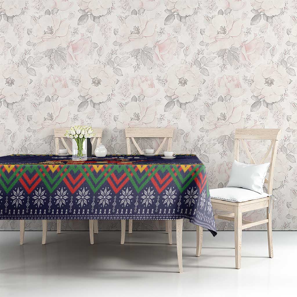 Dark blue tablecloth with colorful folk border over dining table, zigzag and snow motifs
