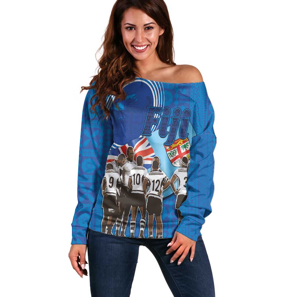 Women’s blue off-shoulder sweater with rugby player graphic and long sleeves—front view.