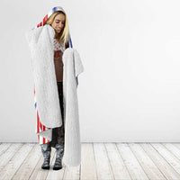 Hooded blanket worn by model, feather jersey print with red/blue stripes and gray fleece lining
