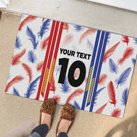 Custom rubber doormat with feather pattern and number 10, shown with shoes on concrete