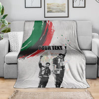 Light gray personalized blanket draped on sofa with green-red brush stripe and “YOUR TEXT”