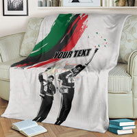Light gray personalized blanket on bed with green-red brush stripe and black-and-white figures