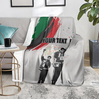 Light gray personalized blanket on sofa with green-red brush stripe and “YOUR TEXT”