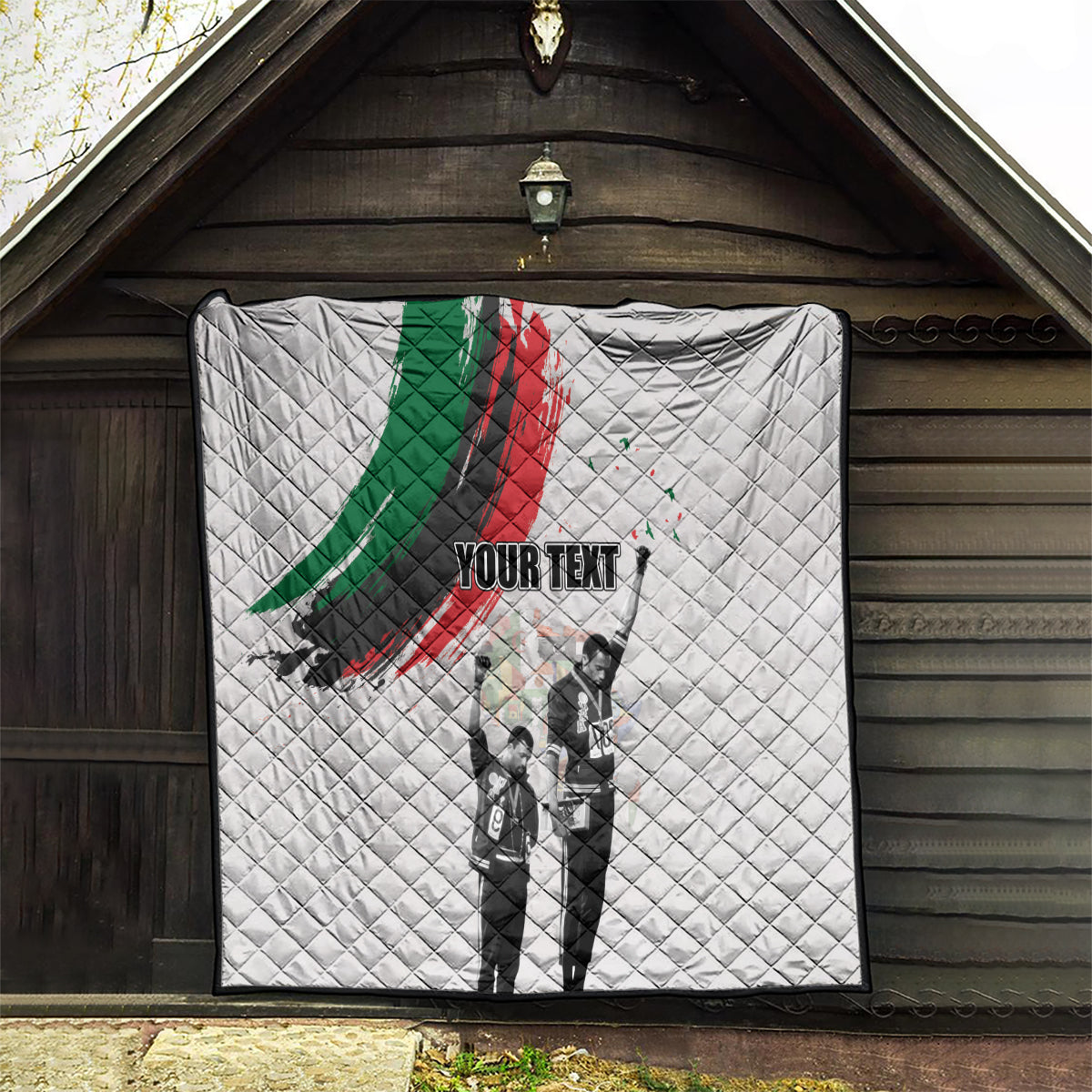 White quilt hanging on porch with green/red brushstroke, black-and-white figures, 'YOUR TEXT'