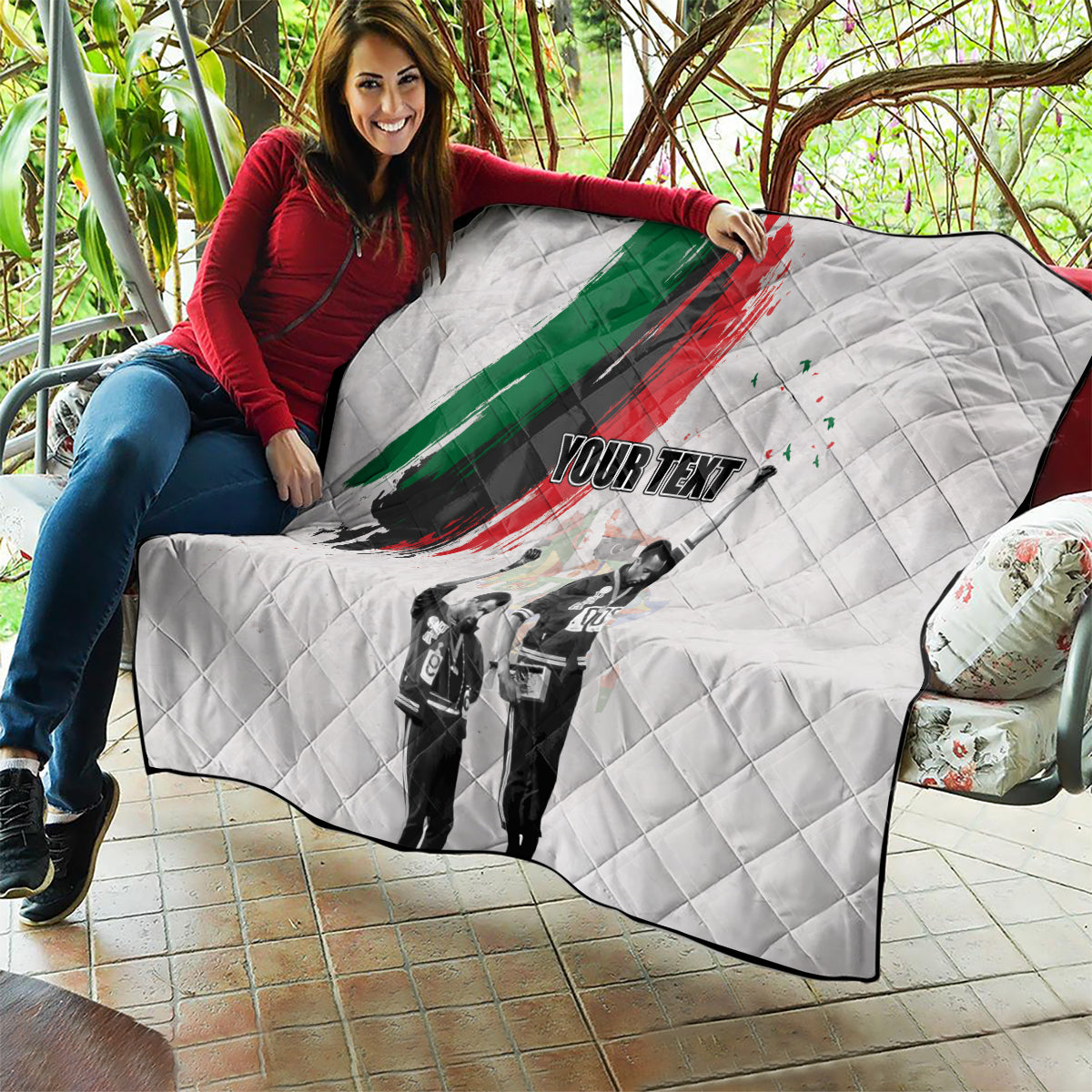 White quilt draped on outdoor seating with green/red brushstroke, black-and-white figures, 'YOUR TEXT'